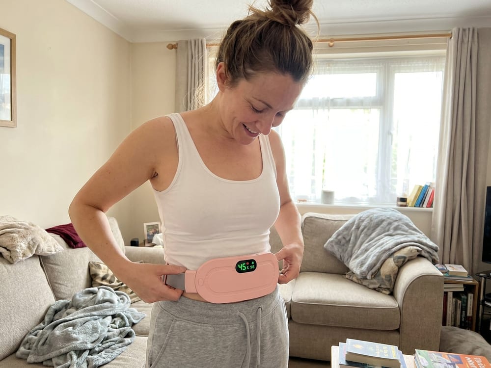 A woman wearing the heating belt around her waist with the pad on her lower belly