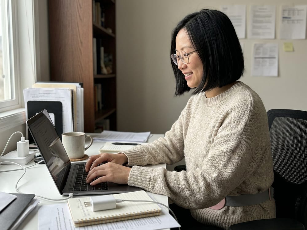 A customer's own photo at her desk, the heating belt hidden under her loose sweater
