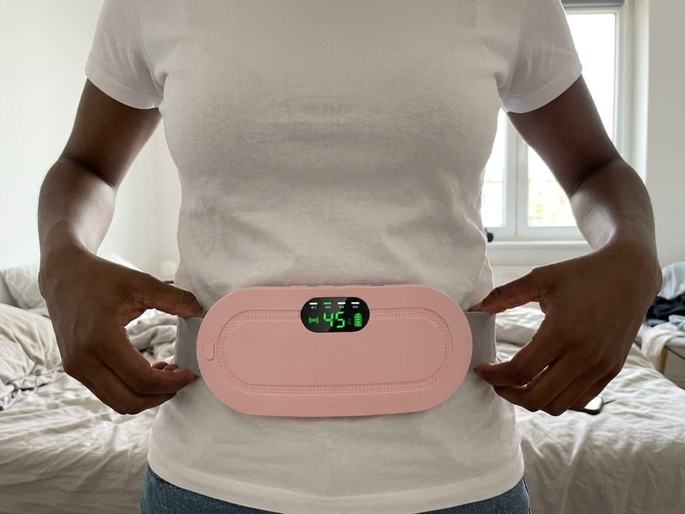 Close-up of the heating pad fastened over a woman's lower belly, the grey strap around her waist